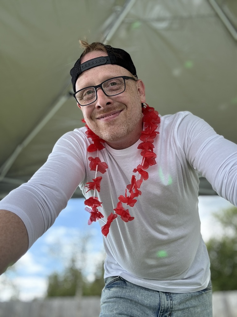 Red On Purpose smiling in a red lei at an Alaska event